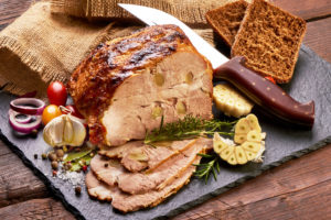 Traditional fresh pork roast, glazed baked spicy meat, close-up, on rustic background
